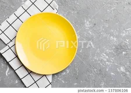 Top view on colored background empty round yellow plate on tablecloth for food. Empty dish on napkin with space for your design Top view on colored background empty round yellow plate on tablecloth for food. Empty dish on napkin with space for your design 137806106