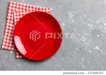 Top view on colored background empty round red plate on tablecloth for food. Empty dish on napkin with space for your design Top view on colored background empty round red plate on tablecloth for food. Empty dish on napkin with space for your design 137806107