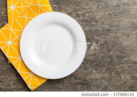 Top view on colored background empty round white plate on tablecloth for food. Empty dish on napkin with space for your design Top view on colored background empty round white plate on tablecloth for food. Empty dish on napkin with space for your design 137806110