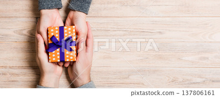 Top view of a couple congratulating each other on wooden background. Giving a present. Festive concept. Copy space 137806161
