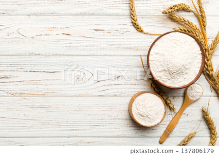 Flat lay of Wheat flour in wooden bowl with wheat spikelets on colored background. world wheat crisis Flat lay of Wheat flour in wooden bowl with wheat spikelets on colored background. world wheat crisis 137806179