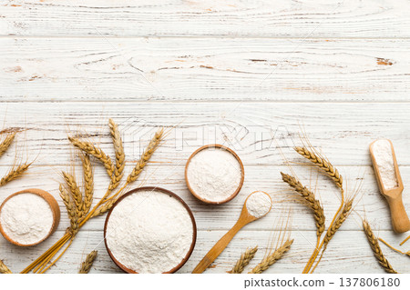 Flat lay of Wheat flour in wooden bowl with wheat spikelets on colored background. world wheat crisis Flat lay of Wheat flour in wooden bowl with wheat spikelets on colored background. world wheat crisis 137806180