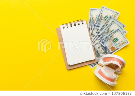 Flat lay composition with educational dental typodont model and money with notebook on colored table, top view. Expensive treatment Flat lay composition with educational dental typodont model and money with notebook on colored table, top view. Expensive treatment 137806182
