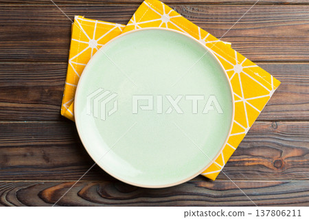 Top view on colored background empty round green plate on tablecloth for food. Empty dish on napkin with space for your design Top view on colored background empty round green plate on tablecloth for food. Empty dish on napkin with space for your design 137806211