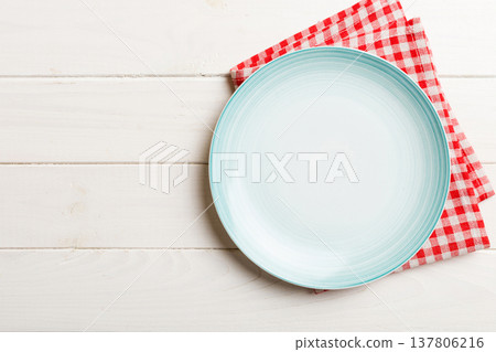 Top view on colored background empty round blue plate on tablecloth for food. Empty dish on napkin with space for your design Top view on colored background empty round blue plate on tablecloth for food. Empty dish on napkin with space for your design 137806216