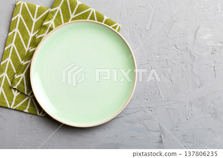 Top view on colored background empty round green plate on tablecloth for food. Empty dish on napkin with space for your design 137806235