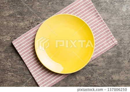 Top view on colored background empty round yellow plate on tablecloth for food. Empty dish on napkin with space for your design Top view on colored background empty round yellow plate on tablecloth for food. Empty dish on napkin with space for your design 137806250