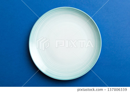 Top view of isolated of colored background empty round blue plate for food. Empty dish with space for your design 137806339