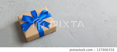 Wrapped christmas or other holiday handmade present in craft paper with colored ribbon. Present box, decoration of gift on table, top view with copy space 137806358