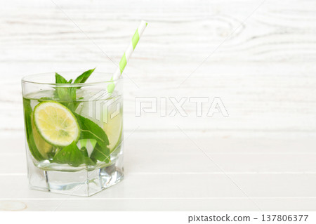 Mojito cocktail. Refreshing mojito cocktail with lime, lemon and mint in a tall glass with a stick Mojito cocktail. Refreshing mojito cocktail with lime, lemon and mint in a tall glass with a stick 137806377