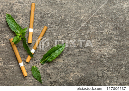 Menthol cigarettes and fresh mint leaves on colored background, Many cigarettes stacked together top view flat lay Menthol cigarettes and fresh mint leaves on colored background, Many cigarettes stacked together top view flat lay 137806387
