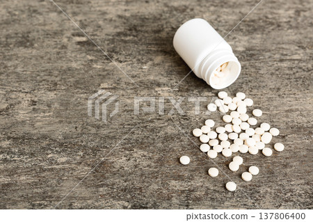 Medicine bottle and white pills spilled on a light background. Medicines and prescription pills flat lay background. White medical pills and tablets spilling out of a drug bottle Medicine bottle and white pills spilled on a light background. Medicines and prescription pills flat lay background. White medical pills and tablets spilling out of a drug bottle 137806400