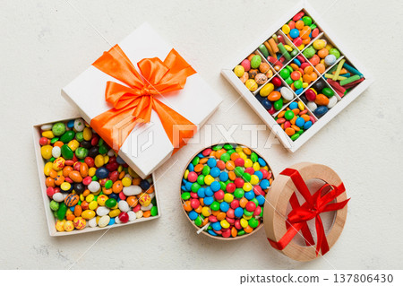 Set of different sweet candy in a paper box with a satin ribbon on a colored background. Holiday concept Set of different sweet candy in a paper box with a satin ribbon on a colored background. Holiday concept 137806430