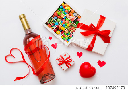 Bottle of red wine on colored background for Valentine Day with gift and chocolate. Heart shaped with gift box of chocolates top view with copy space Bottle of red wine on colored background for Valentine Day with gift and chocolate. Heart shaped with gift box of chocolates top view with copy space 137806473