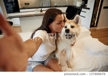 Hand is holding camera, doing selfie. Woman is with her Shibu Inu dog at home Hand is holding camera, doing selfie. Woman is with her Shibu Inu dog at home 137806676