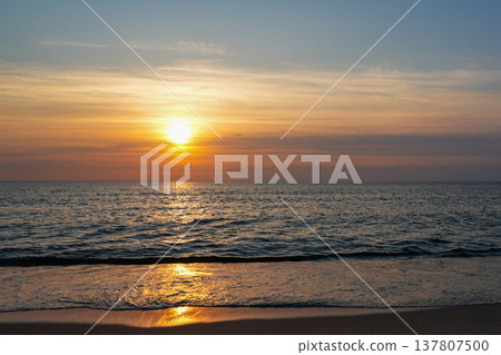 Golden Sunset Over Baltic Sea with Gentle Waves and Warm Evening Light on Sandy Beach Horizon 137807500