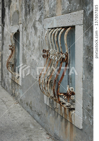Rusty Wrought Iron Window Grilles on Weathered Wall 137807885
