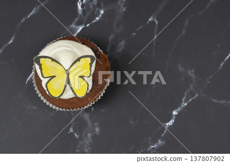 Top View of Chocolate Cupcake with Yellow Butterfly on Dark Marble Top View of Chocolate Cupcake with Yellow Butterfly on Dark Marble 137807902