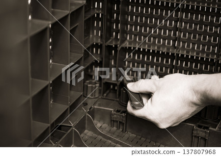 Assembling modular plastic container. A hand inserts a piece into the interlocking system. Assembling modular plastic container. A hand inserts a piece into the interlocking system. 137807968