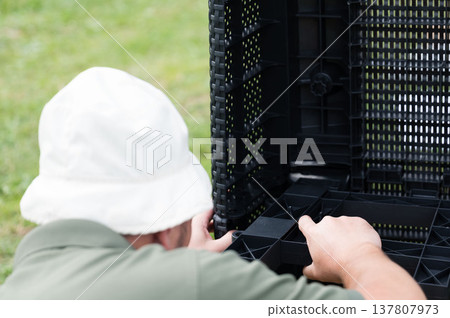 Person assembling outdoor furniture, focusing on connecting plastic components. 137807973