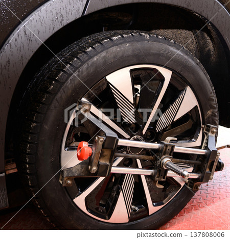 Wheel alignment and alignment on the car service platform. Car wheel alignment process taking place in a workshop with tools and equipment for adjustment 137808006