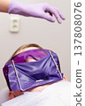 Young patient in a dental clinic prepares for treatment while wearing a protective face shield and goggles during an afternoon appointment in the care of a professional 137808076