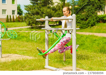 Woman doing exercise in outdoor gym Woman doing exercise in outdoor gym 137808094