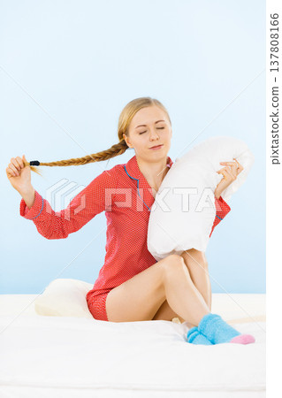 Young woman wearing pajamas hugging soft pillow 137808166