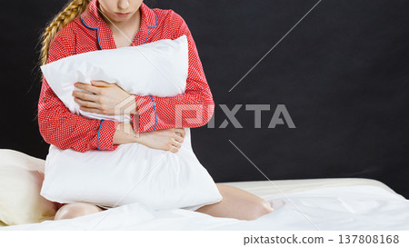 Sad depressed girl in bed gripping pillow Sad depressed girl in bed gripping pillow 137808168