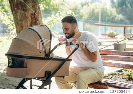 Taking care of baby, looking into a cradle. Father is having a walk in the park Taking care of baby, looking into a cradle. Father is having a walk in the park 137808424