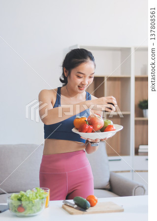 Fit young Asian women in activewear sitting on yoga mat and eating fresh vegetable salad after workout, representing clean eating, fitness lifestyle, wellness routine and health balance. Fit young Asian women in activewear sitting on yoga mat and eating fresh vegetable salad after workout, representing clean eating, fitness lifestyle, wellness routine and health balance. 137808561