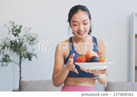 Fit young Asian women in activewear sitting on yoga mat and eating fresh vegetable salad after workout, representing clean eating, fitness lifestyle, wellness routine and health balance. Fit young Asian women in activewear sitting on yoga mat and eating fresh vegetable salad after workout, representing clean eating, fitness lifestyle, wellness routine and health balance. 137808562