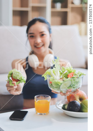 Fit young Asian women in activewear sitting on yoga mat and eating fresh vegetable salad after workout, representing clean eating, fitness lifestyle, wellness routine and health balance. Fit young Asian women in activewear sitting on yoga mat and eating fresh vegetable salad after workout, representing clean eating, fitness lifestyle, wellness routine and health balance. 137808574