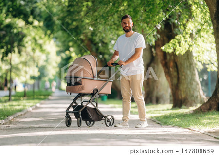 Happy parent. Father is with cradle, having a walk in the park Happy parent. Father is with cradle, having a walk in the park 137808639