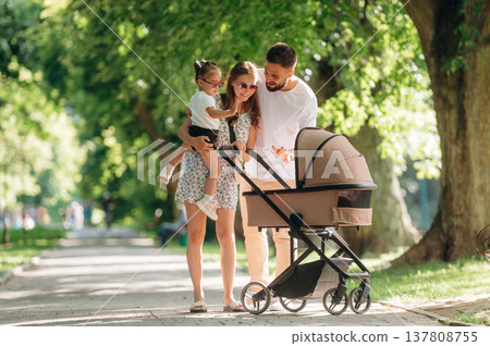 Family conception. Couple is with daughter and cradle are having a walk Family conception. Couple is with daughter and cradle are having a walk 137808755