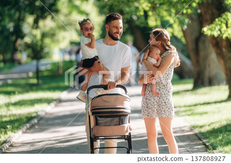 Little baby in hands. Couple is with daughter, newborn baby and cradle are having a walk 137808927