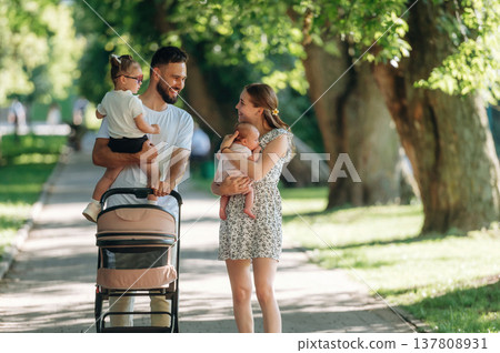 Little baby in hands. Couple is with daughter, newborn baby and cradle are having a walk 137808931