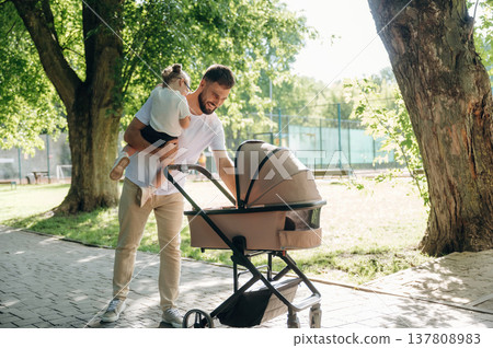 Man with his daughter and cradle in the park Man with his daughter and cradle in the park 137808983