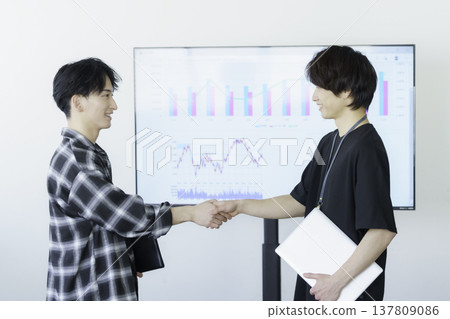 一位身著便服的年輕男子與人握手。 137809086