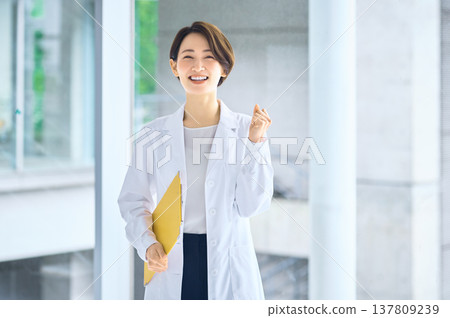 A woman in a white coat smiles and makes a victory pose. (Medical/research image) A woman in a white coat smiles and makes a victory pose. (Medical/research image) 137809239