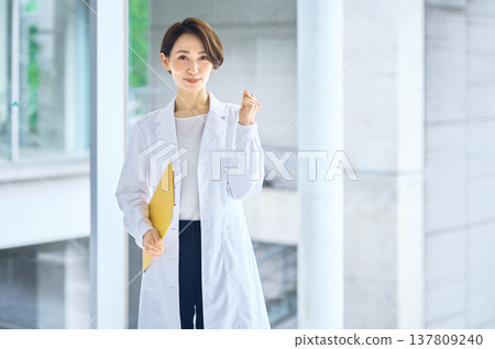A woman in a white coat making a victory pose; a medical professional, doctor, or pharmacist. A woman in a white coat making a victory pose; a medical professional, doctor, or pharmacist. 137809240
