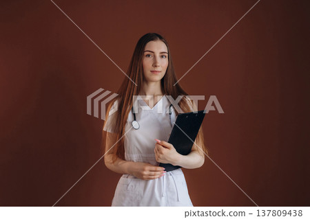 Notepad is in hand. Female doctor is in the studio 137809438