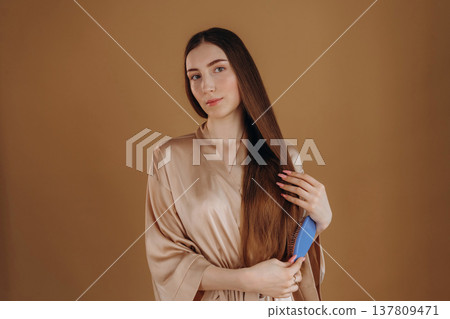 Combs her hair, brushing. Young woman is against background Combs her hair, brushing. Young woman is against background 137809471
