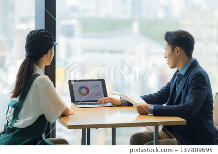 一名身穿西裝的男子正在與一名在咖啡館工作的女子會面。 137809695