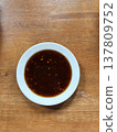 Soy sauce dipping sauce asian food brown liquid white bowl wooden table salty flavor traditional recipe closeup overhead view savory condiment adds rich depth to simple meal presentation 137809752
