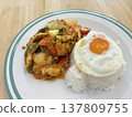 Thai stir fry rice fried egg egg yolk white plate home cooked comfort food lunch dinner rustic table homemade Thai stir fry with rice and fried egg white plate over rustic wooden table 137809755
