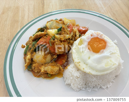 Thai stir fry rice fried egg egg yolk white plate home cooked comfort food lunch dinner rustic table homemade Thai stir fry with rice and fried egg white plate over rustic wooden table 137809755