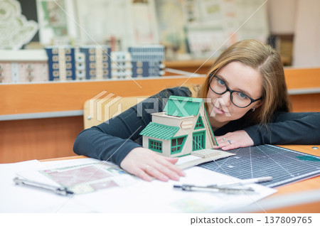 Caucasian young woman making a model of a building. Student of the construction university.  137809765