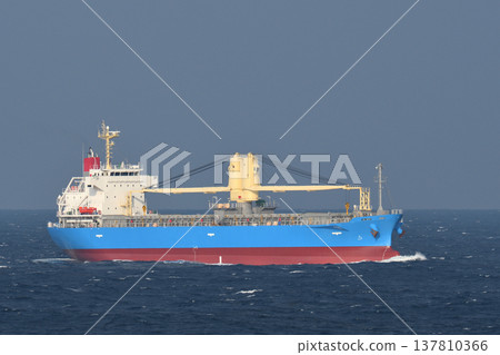一艘貨船航行在陰雲密佈的海面上。 137810366