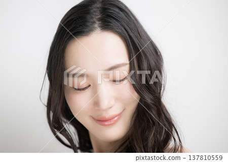 一位長著黑色燙髮的女子在白色背景下飄逸;這是一張關於頭髮護理和治療的圖片。 一位長著黑色燙髮的女子在白色背景下飄逸;這是一張關於頭髮護理和治療的圖片。 137810559